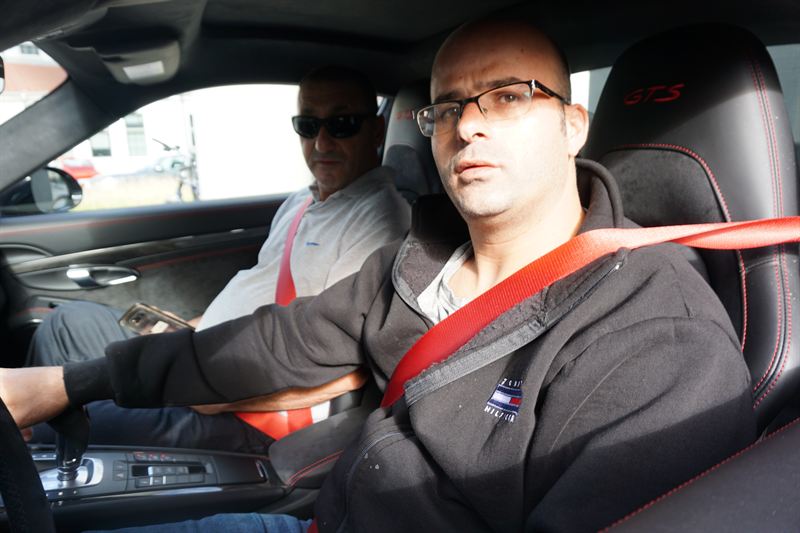 Niro Sharon and a tour guest in a Porsche 911 GTS cabin, red seat belts