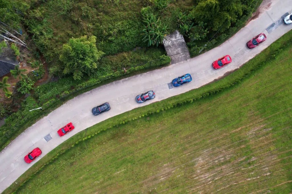 Group of sales leaders standing beside a row of Porsche 911s on a mountain road in Italy